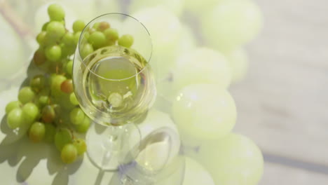 compuesto de vaso de vino blanco sobre uvas blancas en superficie de madera