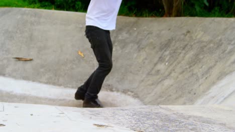 Low-section-of-young-man-doing-skateboarding-trick-on-ramp-in-skateboard-park-4k