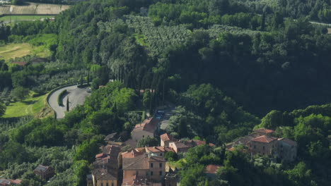 lush green hills and houses in lorenzana, italy under a clear summer sky, aerial view