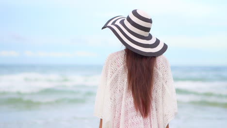 Lonely-woman-standing-in-front-of-ocean-waves-and-looking-at-horizon,-back-view