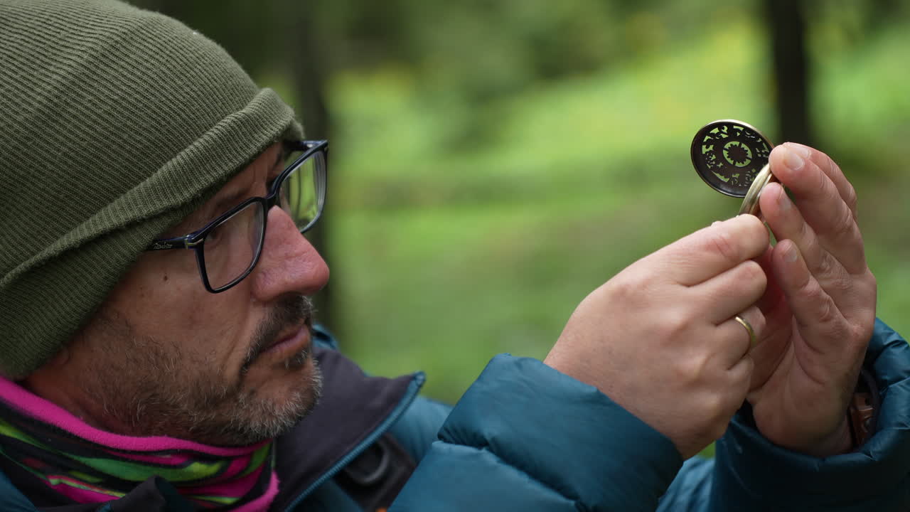 Man wearing glasses and winter clothes using compass in forest