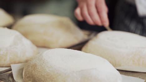 closeup, the baker cuts through and decorates the raw homemade bread before baking in the oven