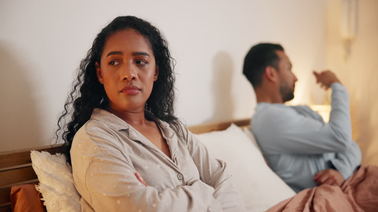 una pareja discutiendo en la cama.
