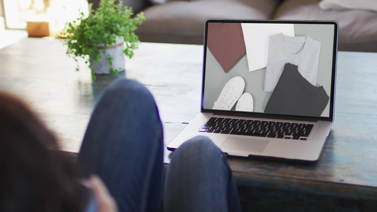 Ginocchia di donna al tavolo che usa un laptop, shopping online di vestiti, in slow motion.