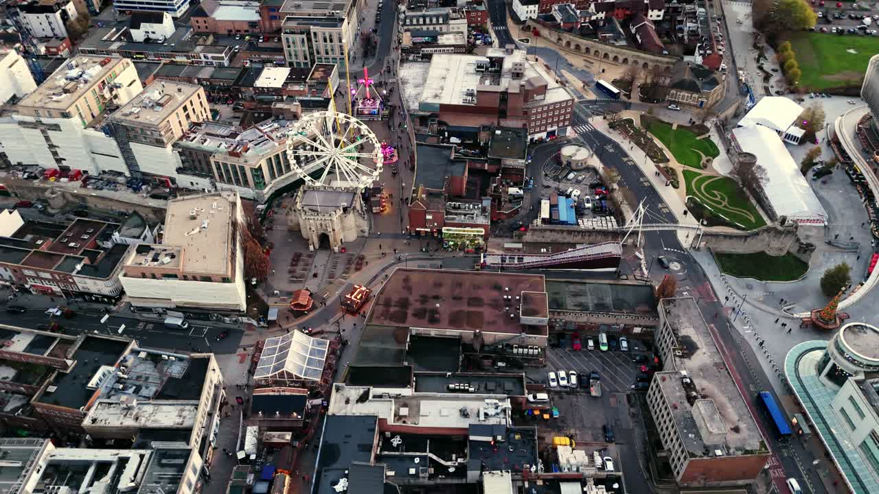 Aerial landscape drone shot panning over Southampton’s Christmas Market, capturing rows of festive stalls, a brightly lit ferris wheel, and crowds exploring the lively city winter scene