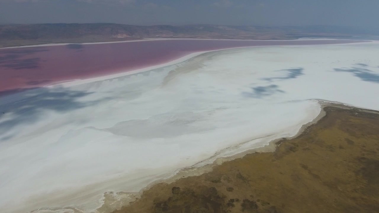 Flyfoto av rosa saltsjø og tørt landskap