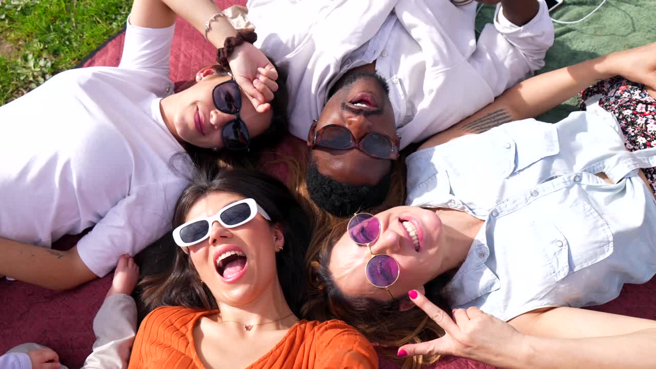 Group of friends lying down on a blanket and having fun