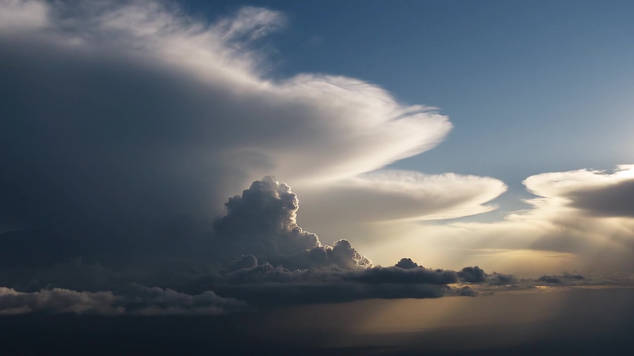 Dramatic towering anvil cloud formation under a clear blue sky