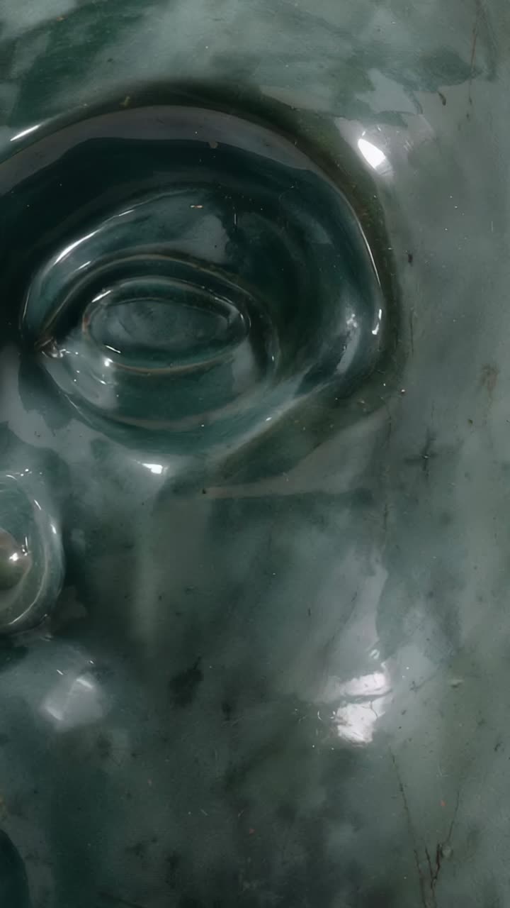 Vertical video: Pulling back camera revealing green face sculpture in studio to reveal veins