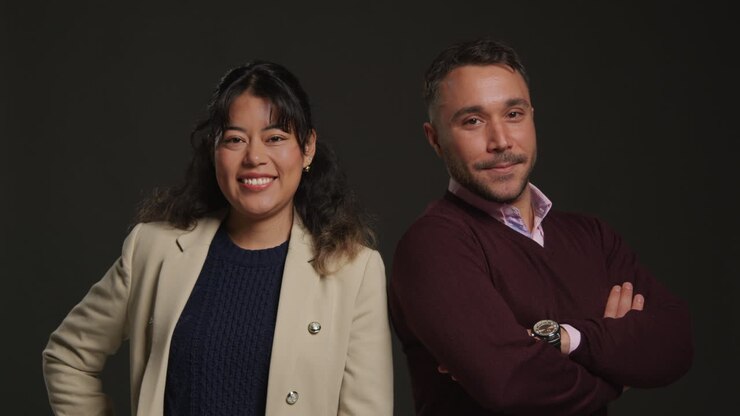 Studio Portrait Of Smiling Male And Female Teachers Standing Against Black Background