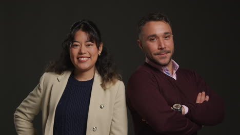 Studio-Portrait-Of-Smiling-Male-And-Female-Teachers-Standing-Against-Black-Background