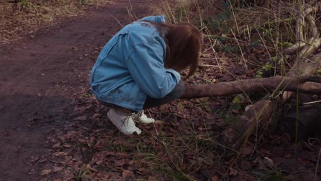 girl squating next to a tree in a forrest