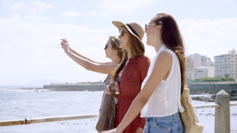 three young women tourists on summer vacation walking on beach promenade