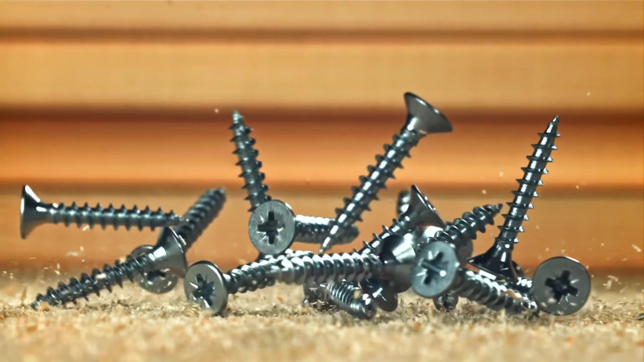 Metal Screws Falling in Slow Motion onto Sawdust