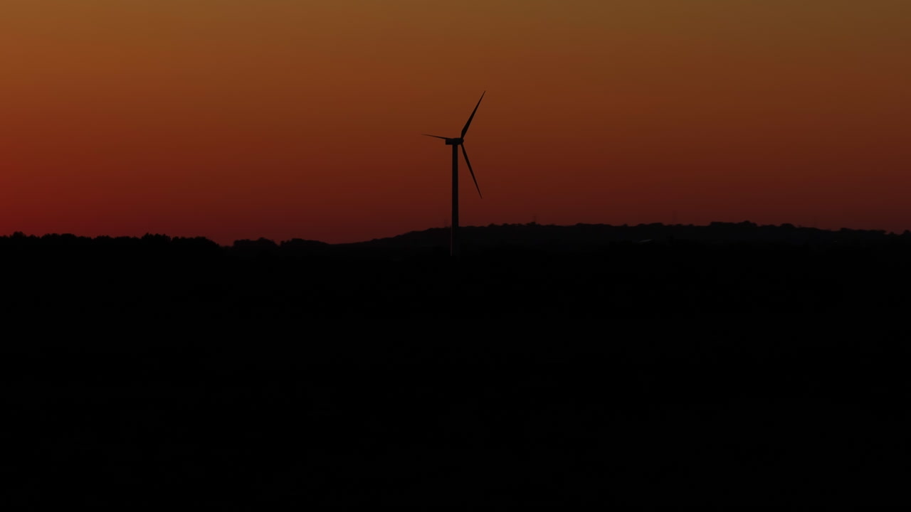 풍력 터빈을 특징으로 하는 매혹적인 해가 지는 드론 영상