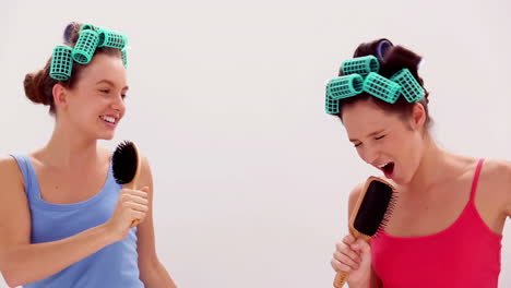 amigos en rodillos de pelo cantando en sus cepillos de pelo