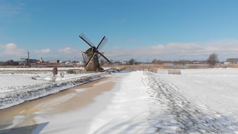 Traditional-winter-Dutch-windmill-scene-and-frozen-canal,-aerial-view