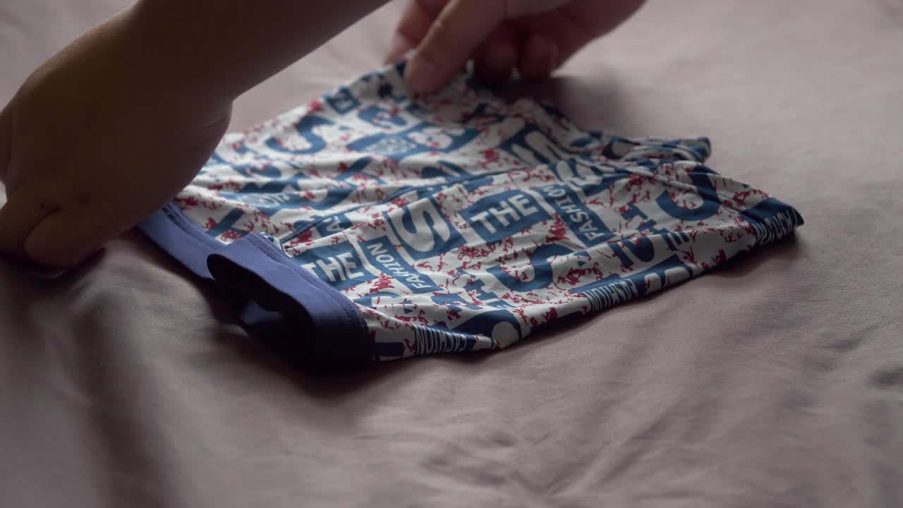 los hombres usan sus manos para doblar la ropa interior masculina para mantenerla organizada y fácil de guardar y usar