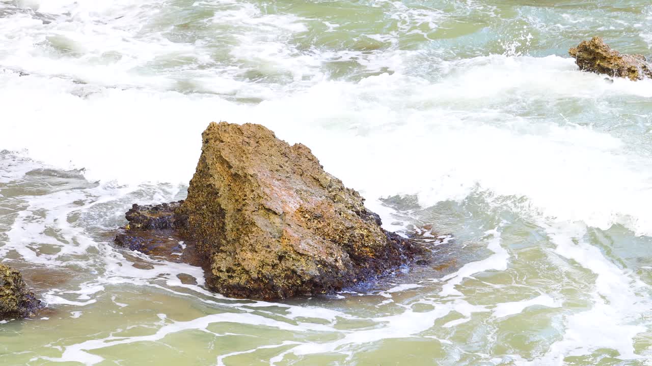 Dynamic ocean waves crash against rugged rocks at Loch Ard Gorge, creating a dramatic and powerful coastal scene