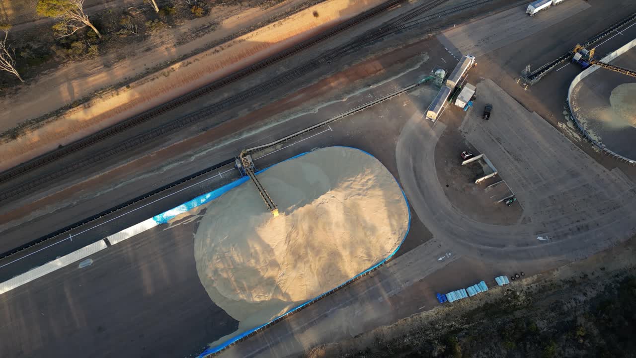 Autocarro con nastro trasportatore per cereali che versa il suo contenuto in un deposito a cielo aperto, vista aerea dall'alto