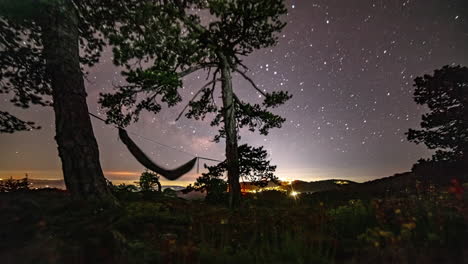 starry night sky over mount olympos in cyprus with traveler and hammock in silhouette