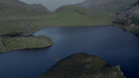 drone flyover of the island in llyn y dywarchen lake, north wales. also called turf island or floating island, this rural landscape is linked to tylwyth teg welsh folklore and ancient legends