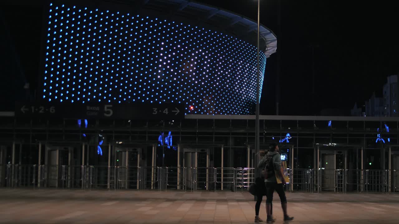 vista nocturna de una arena con personas caminando hacia la entrada