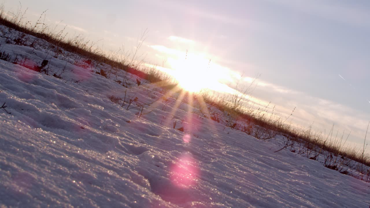 A dutch-tilted landscape wide shot created in establishment shot format. The sun peaks across the far horizon line creating clean focal distortion in the lens. The ground is icy tundra.