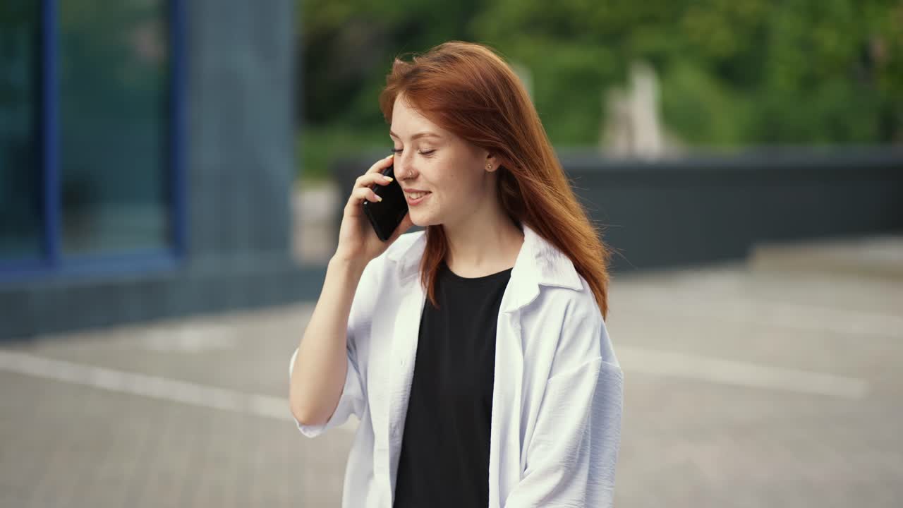 ⁇ 은 머리카락의 소녀가 거리를  ⁇ 고 전화로 이야기합니다.