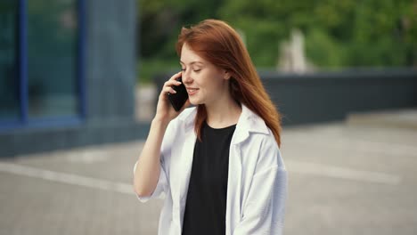 Red-haired-girl-walks-down-the-street-and-talks-on-the-phone