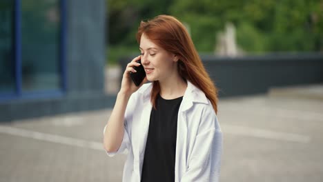 red-haired girl walks down the street and talks on the phone