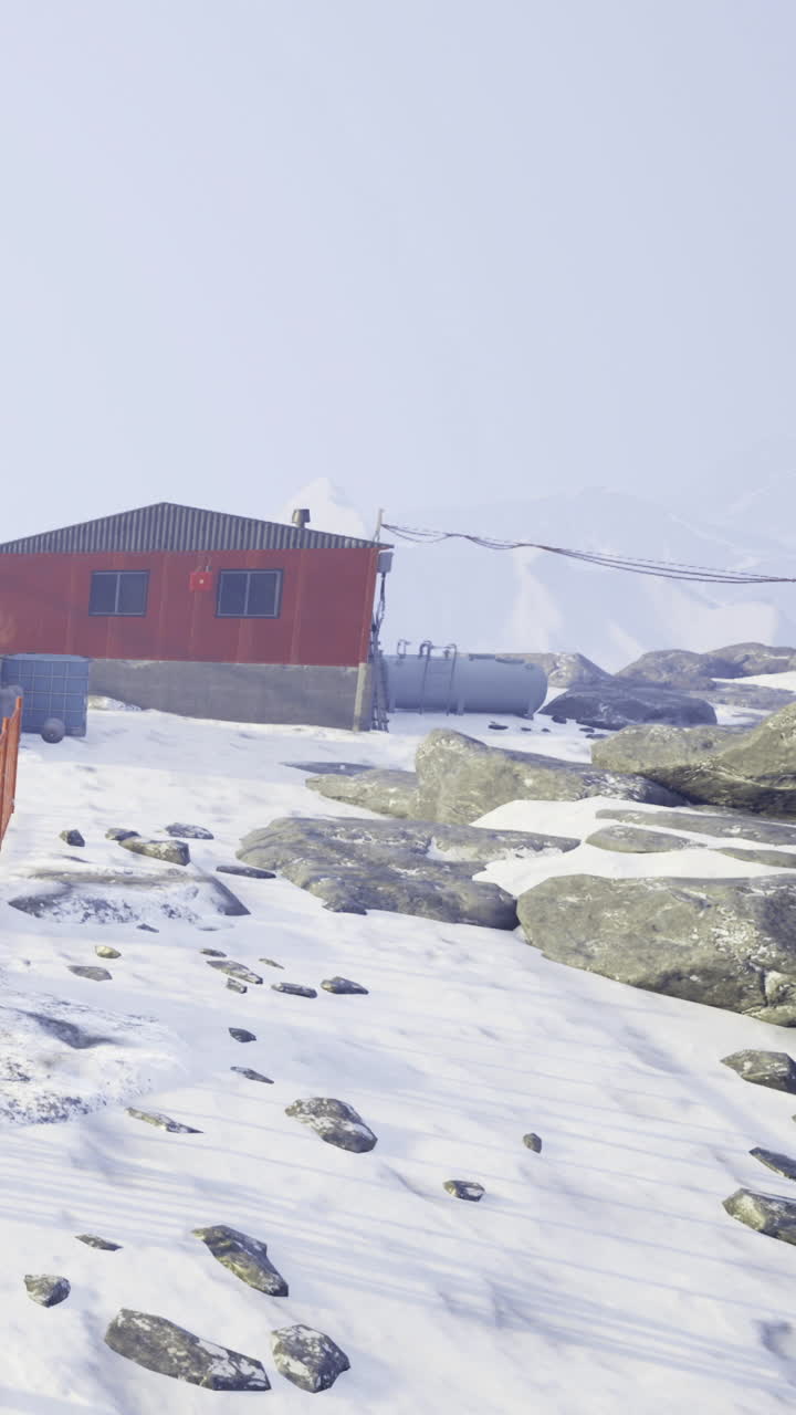Paisaje nevado con una cabaña naranja bajo un cielo nublado.
