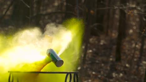 yellow spray paint can being shot in slow motion by which it explodes and splatters aerosol paint everywhere under high pressure and begins to fly around because of it