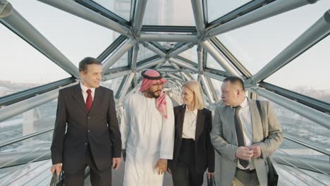 successful multi-ethnic business people walking along glass bridge