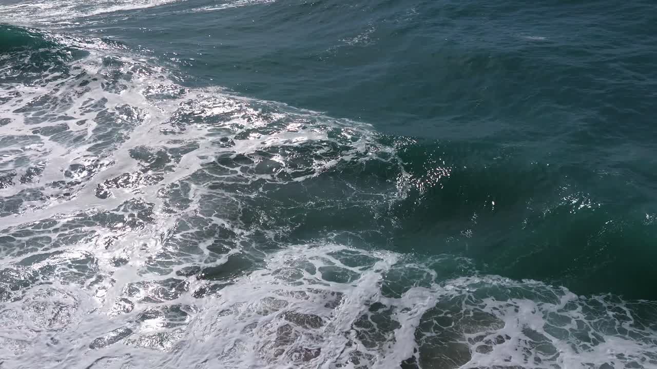 Onde marine che si trascinano su una superficie bianca e spumosa.