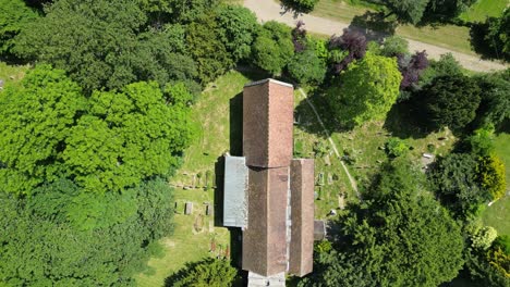 An-orange-tiled-rooftop-of-a-church-surrounded-by-lush-green-trees-in-the-village-of-Littlebourne,-Kent,-England