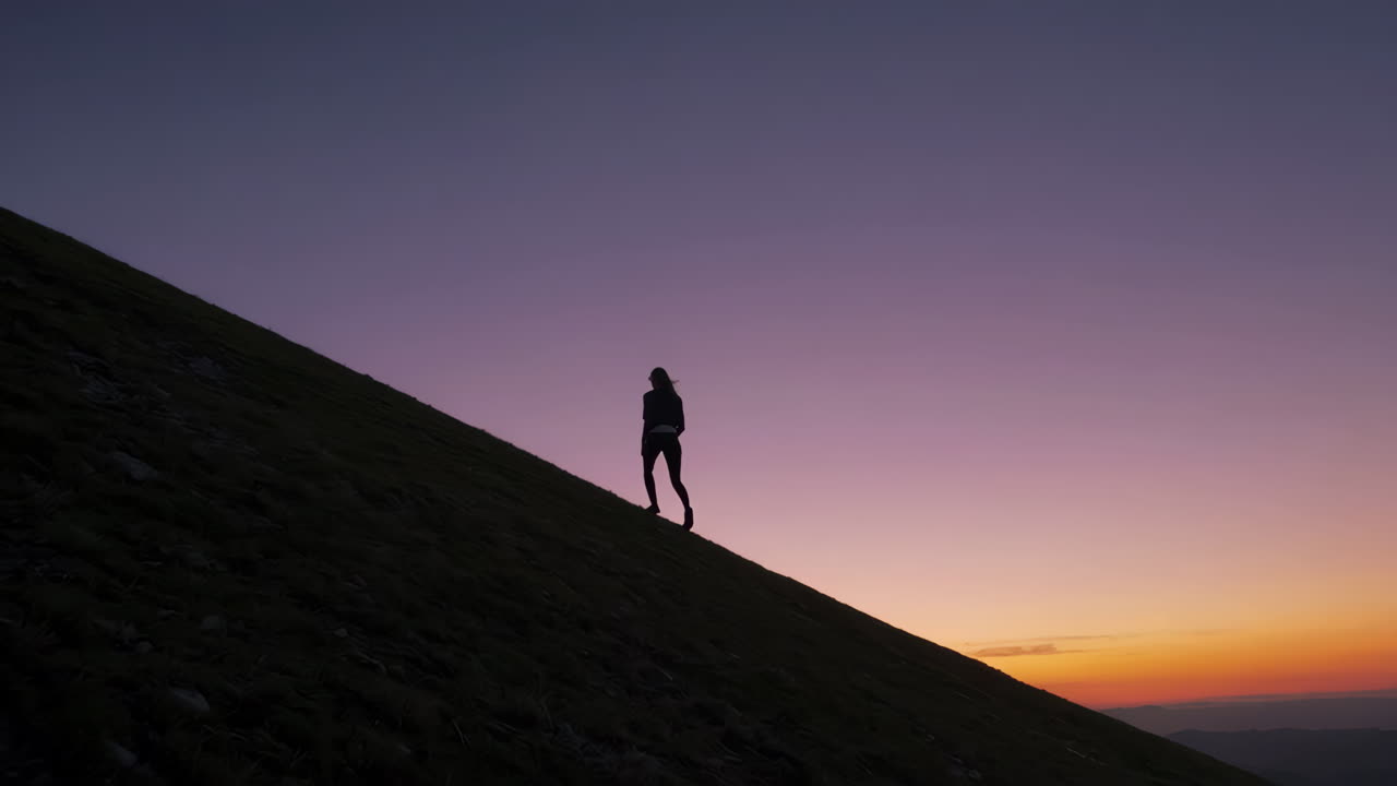 mujer caminando por la montaña al atardecer