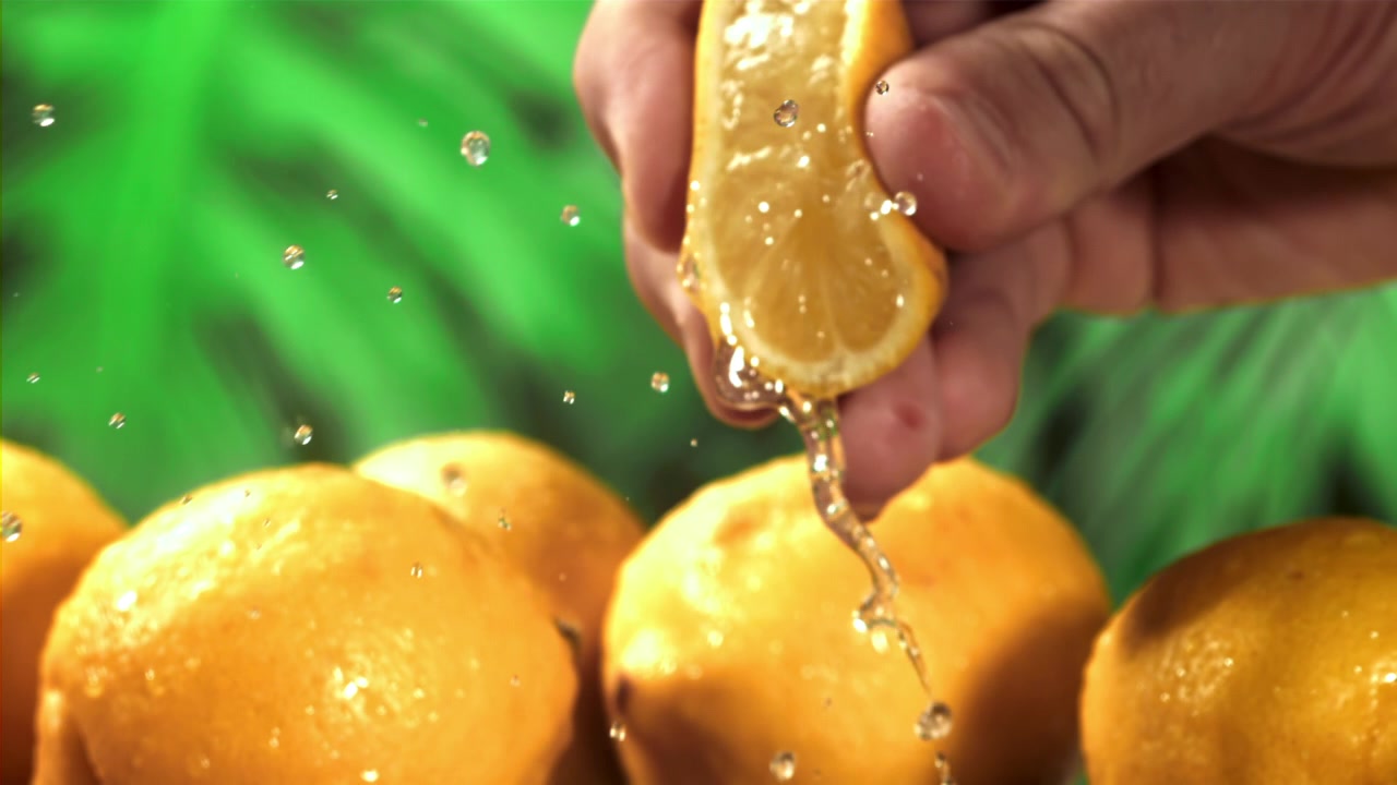 Hand Squeezing Fresh Lemon Half with Juice Dripping in Slow Motion