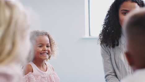 Female-infant-school-teacher-sitting-in-the-classroom-talking-to-children,-close-up,-selective-focus