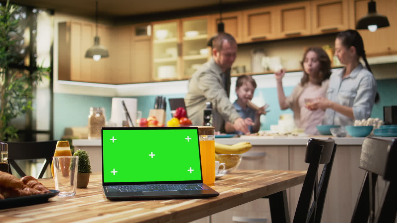 Green screen on laptop near parents and kids preparing homemade pizza