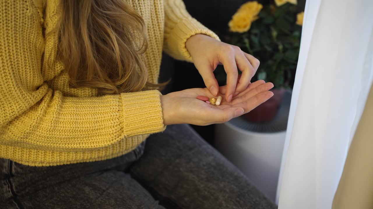 She carefully chooses a pill from her open hand, highlighting the moment of decision. The focus is on the pill she picks, showing attention and mindful selection