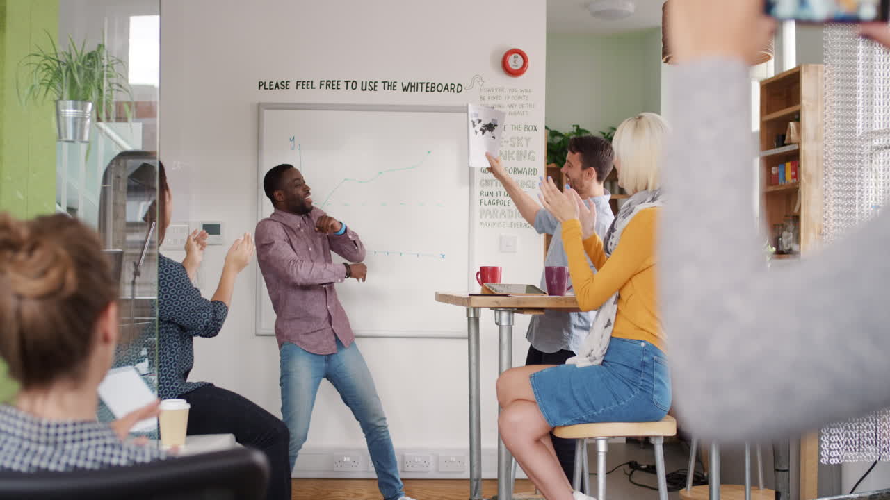 Crazy happy african american businessman dancing doing victory dance in team meeting celebrating success achievement