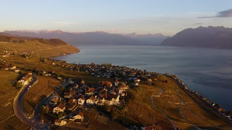 Luftorbit-Hoch-über-Den-Weinbergen-Grandvaux-Und-Lavaux,-Dem-Genfersee-Und-Den-Alpen-Im-Hintergrund,-Orangefarbenes-Sonnenuntergangslicht-Und-Herbstfarben