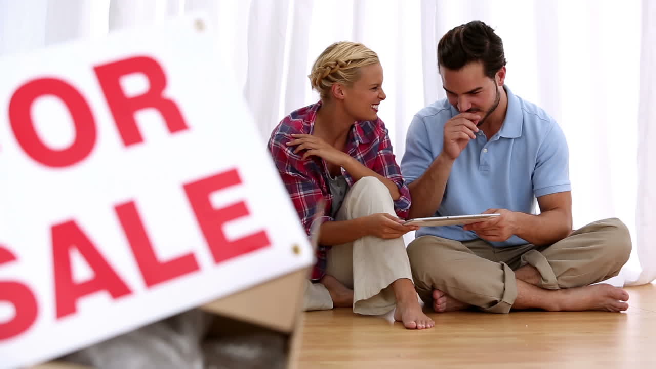 Couple sitting on floor using digital tablet