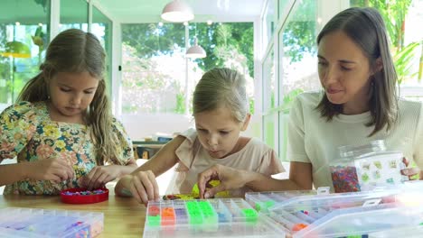 mother and daughters beading together