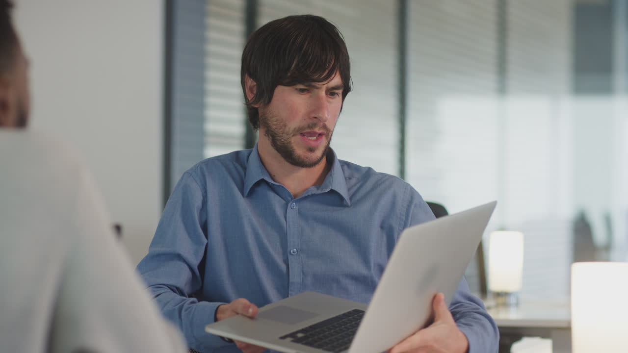 dos hombres de negocios trabajando en escritorios en computadoras portátiles discutiendo el documento en la pantalla en una oficina moderna