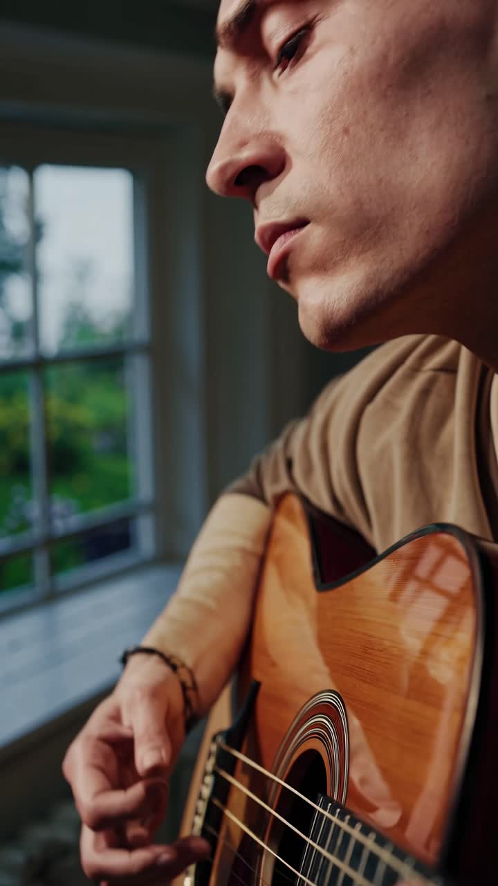 Primo piano di una persona che suona una chitarra acustica in interni.
