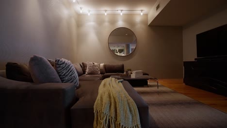 Wide-panning-shot-of-a-cozy-home-nook-with-circular-mirror,-L-shaped-couch,-and-television