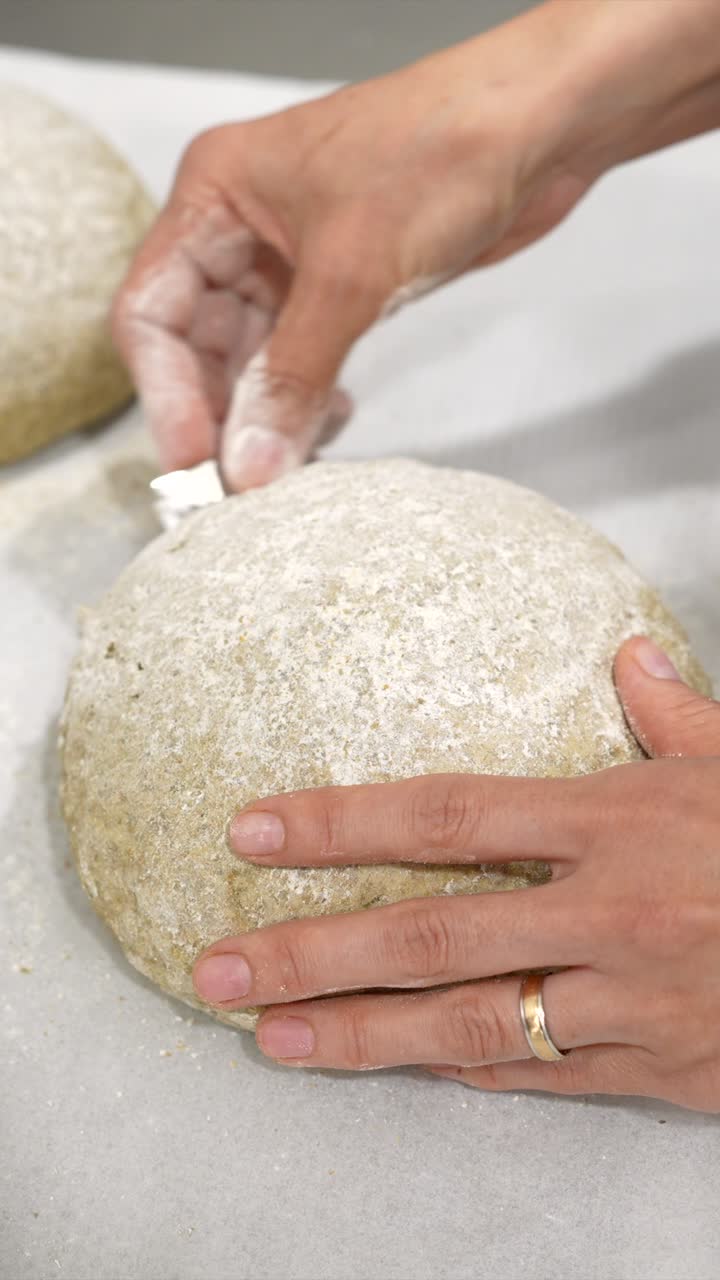 Close-Up of Hands Scoring Raw Bread Dough with a Razor Blade