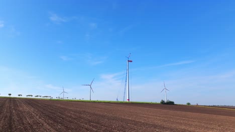 Flying-Towards-Wind-Farm-With-Wind-Tower-Under-Construction-During-Sunset